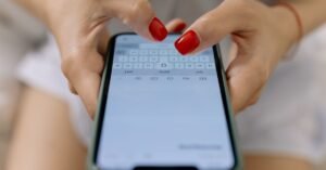 Close de mãos digitando mensagem na tela de um celular