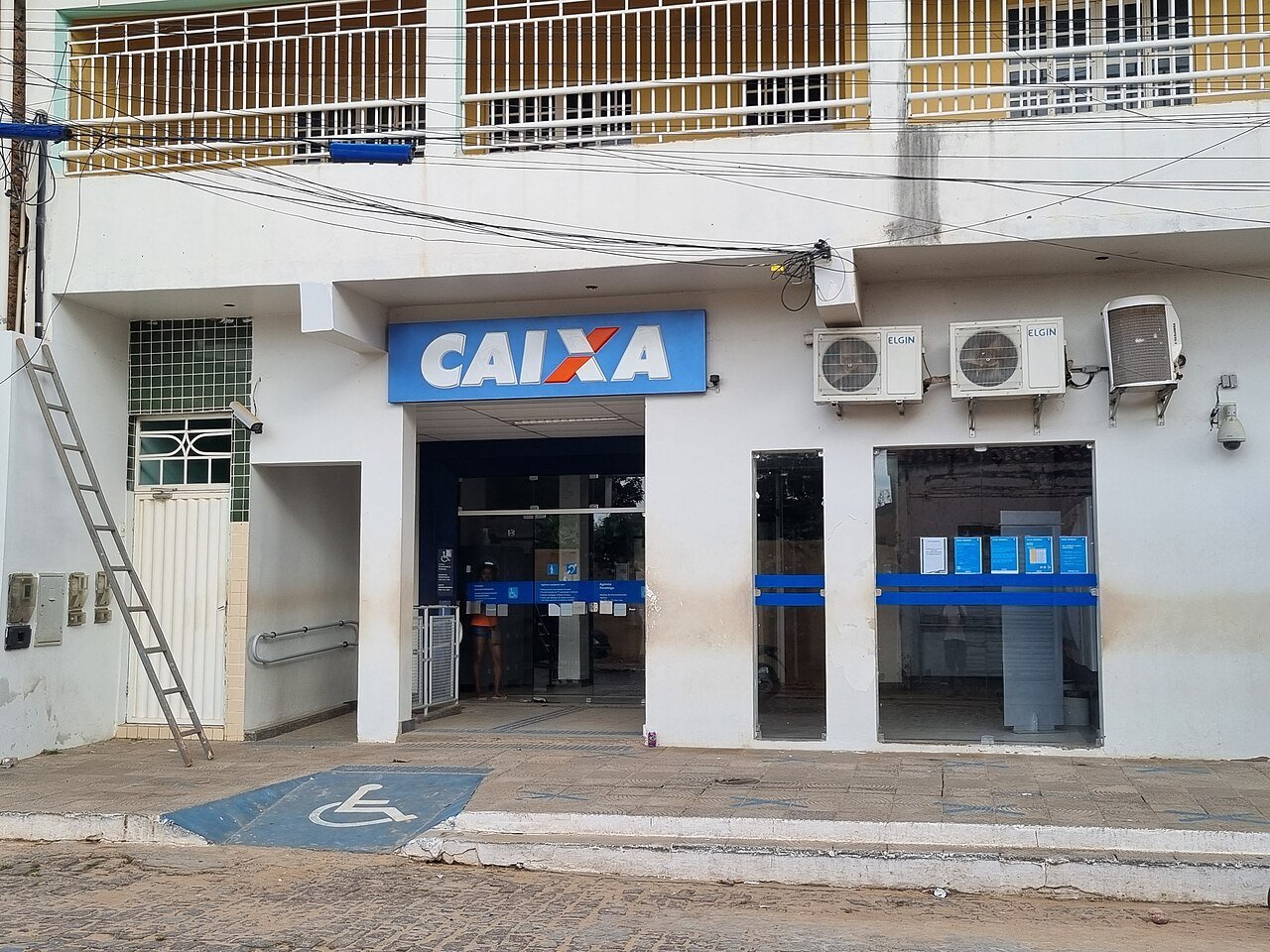 Fachada de agência da Caixa Econômica Federal com o letreiro azul sobre a porta de entrada