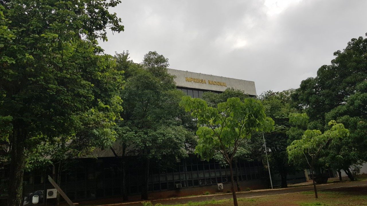 Fachada do prédio da Imprensa Nacional em Brasília, com o letreiro em letras douradas, vista entre árvores