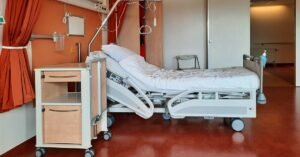 Leito hospitalar vazio em quarto de internação, com equipamentos ao lado
