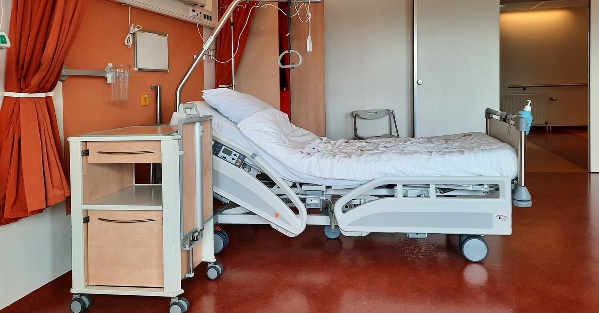 Leito hospitalar vazio em quarto de internação, com equipamentos ao lado