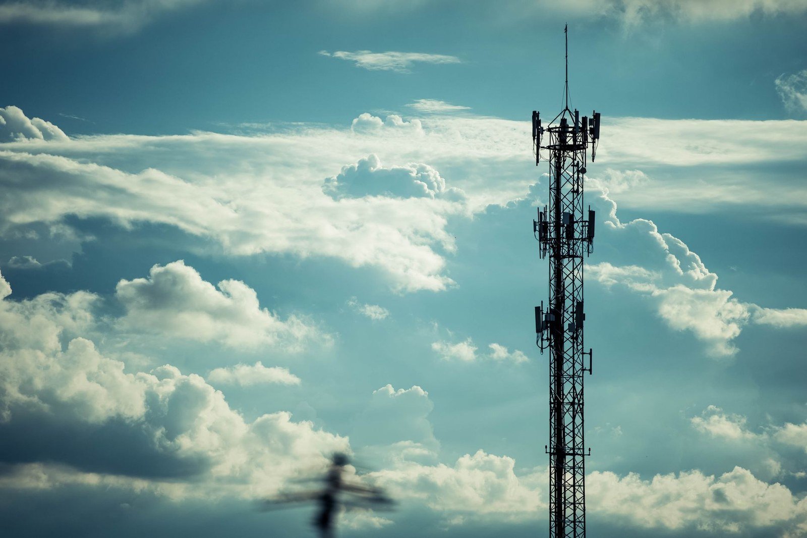 Torre de telecomunicações com antenas recortada contra o céu nublado