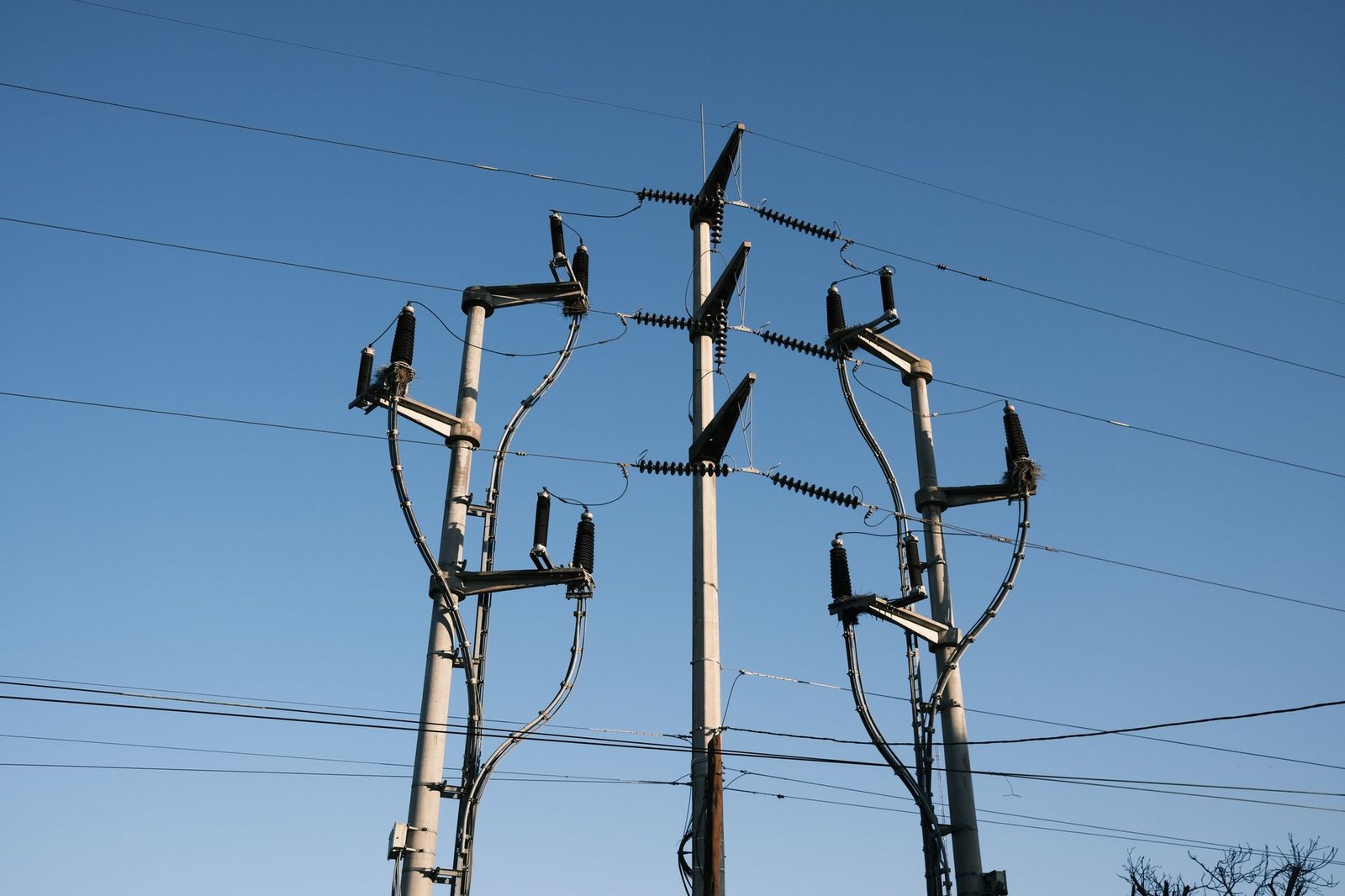 Postes de distribuição de energia elétrica com fios e isoladores contra o céu azul