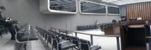 Plenário de julgamento do TJDFT com fileiras de cadeiras vazias e pessoas de toga ao fundo