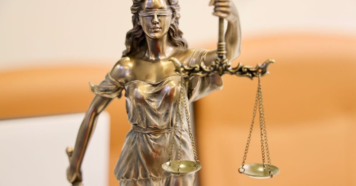Estátua da deusa da Justiça em bronze, vendada e segurando uma balança