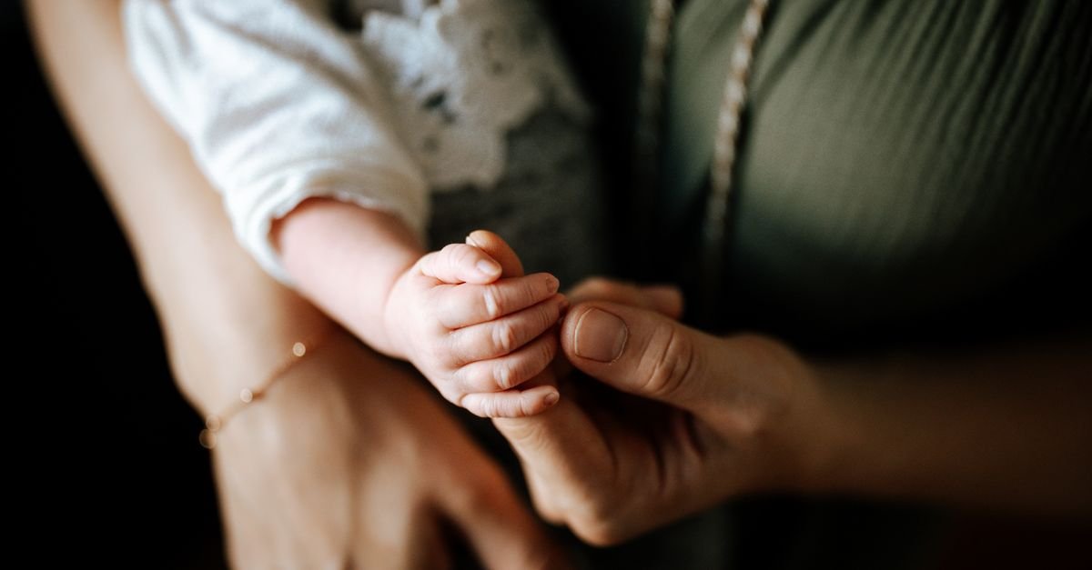 Mão de mãe segurando a mão de um bebê recém-nascido em closeup