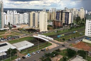Trem do Metro-DF em trecho de superficie, com predios residenciais de Aguas Claras ao fundo