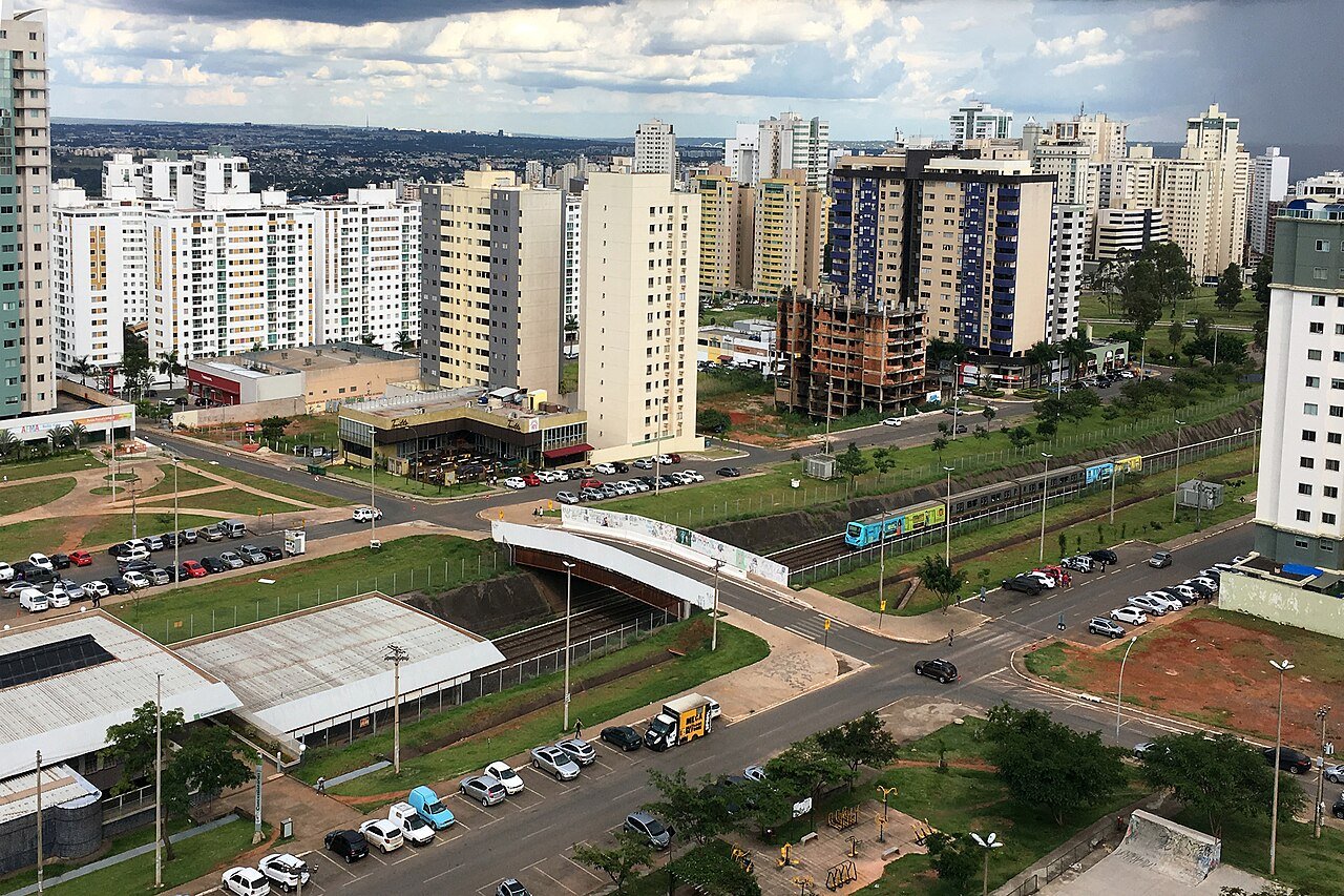 Trem do Metro-DF em trecho de superficie, com predios residenciais de Aguas Claras ao fundo