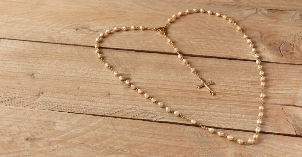 Terço dourado com crucifixo estendido sobre uma mesa de madeira clara