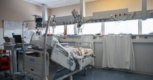 Leito de UTI com monitores e equipamentos médicos em quarto de hospital