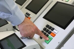 Dedo pressiona a tecla confirma de uma urna eletrônica brasileira