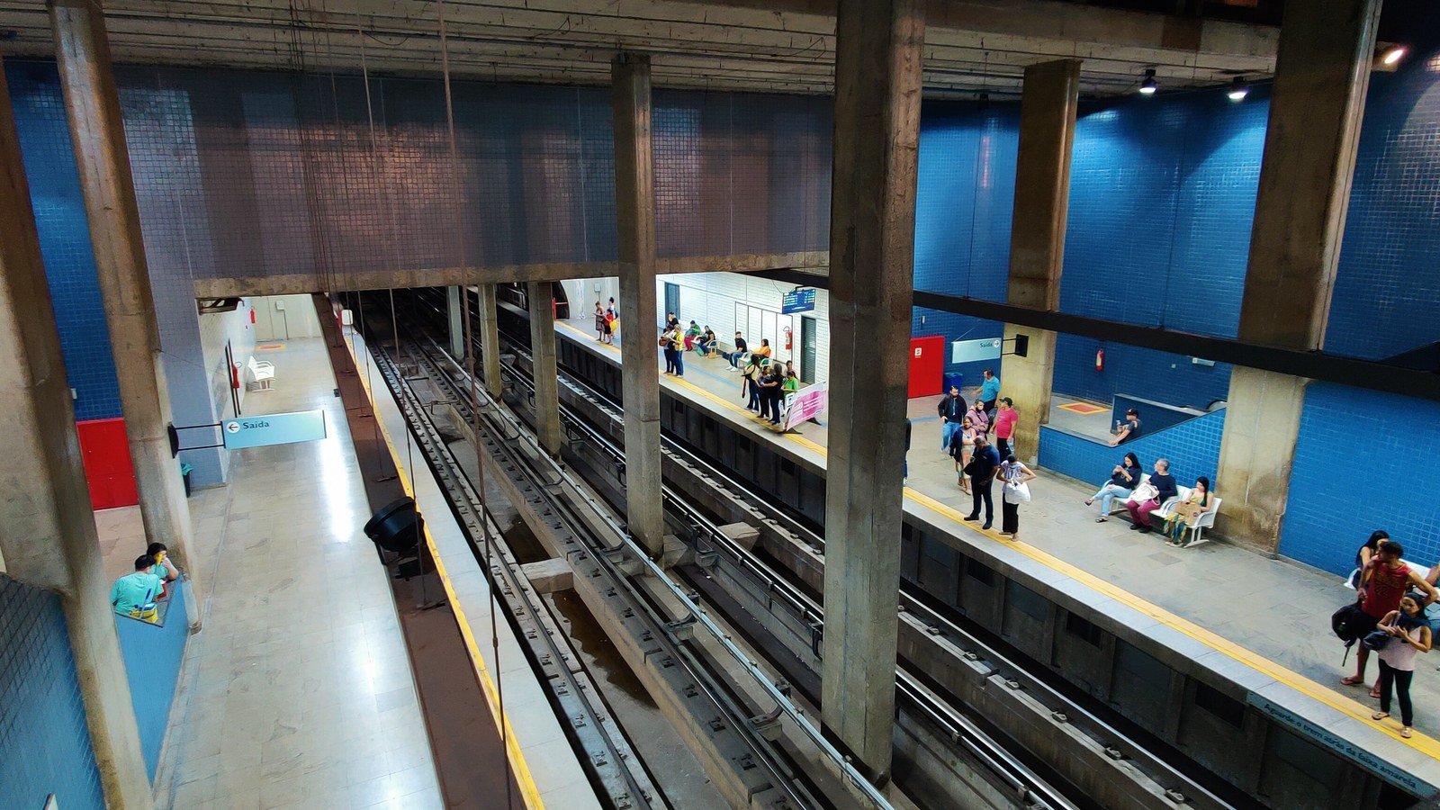 Plataforma da estação Central do Metrô-DF com passageiros esperando o trem e a placa de saída