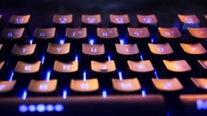 Teclado de computador iluminado por luz azul em ambiente escuro