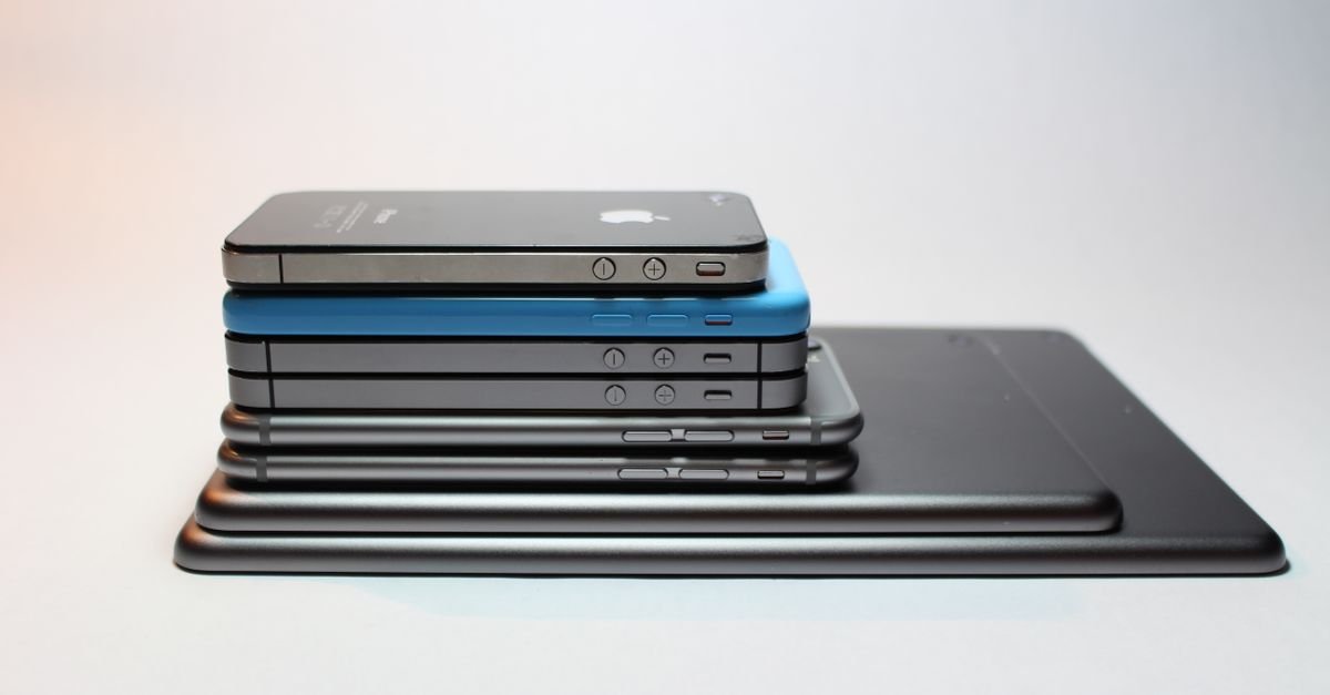 Pilha de celulares e tablets empilhados sobre superfície clara