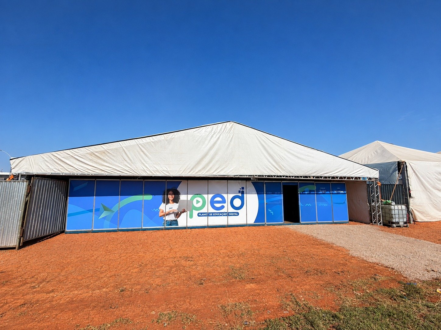 Estrutura de lona branca com fachada azul do PED, montada em terreno de terra em Ceilândia Norte