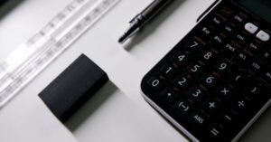 Calculadora científica, régua, borracha e lapiseira sobre mesa branca