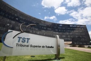 Placa com a sigla TST e o nome Tribunal Superior do Trabalho diante do edifício-sede do tribunal, em Brasília