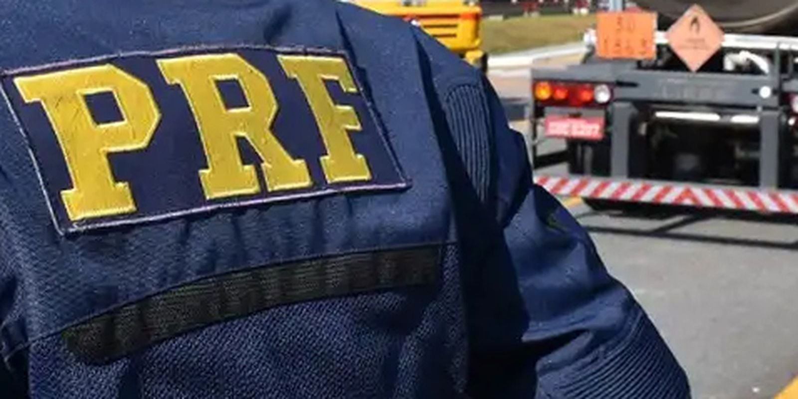 Colete azul com a inscrição PRF em policial rodoviário federal durante fiscalização