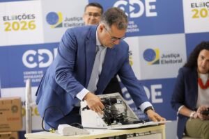 Tecnico abre urna eletronica diante de painel do Centro de Divulgacao das Eleicoes 2026