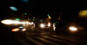 Faróis de carros em movimento em via urbana ao anoitecer, em foto de longa exposição