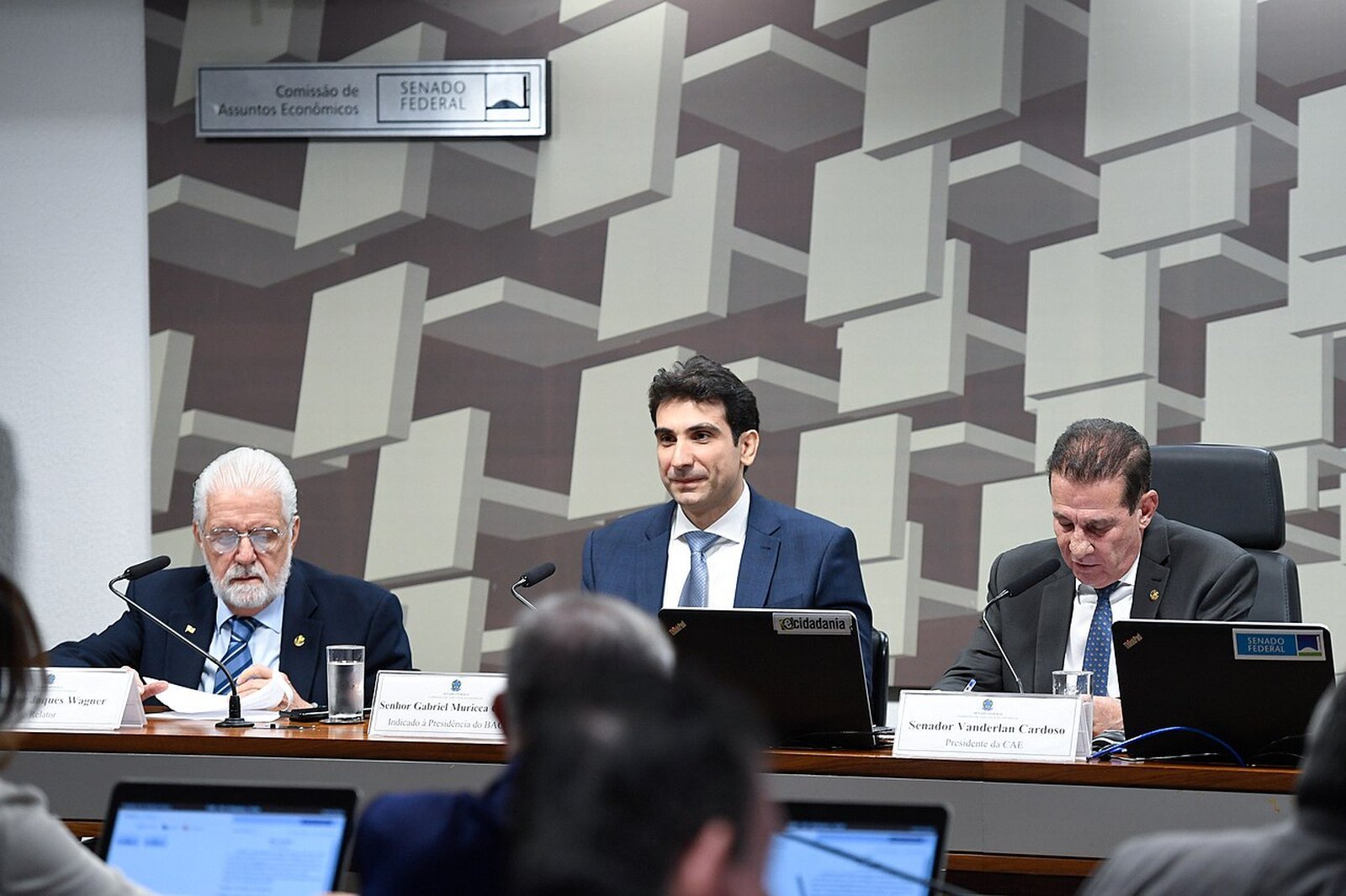 Gabriel Galípolo em sabatina na Comissão de Assuntos Econômicos do Senado, sentado à mesa entre dois senadores