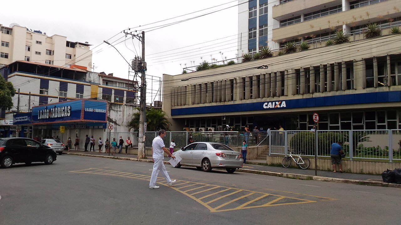 Fachada de agência da Caixa Econômica Federal em rua movimentada