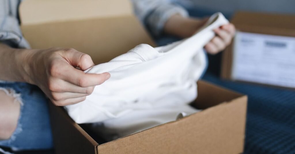 Mulher retira peca de roupa branca de caixa de papelao de encomenda comprada pela internet