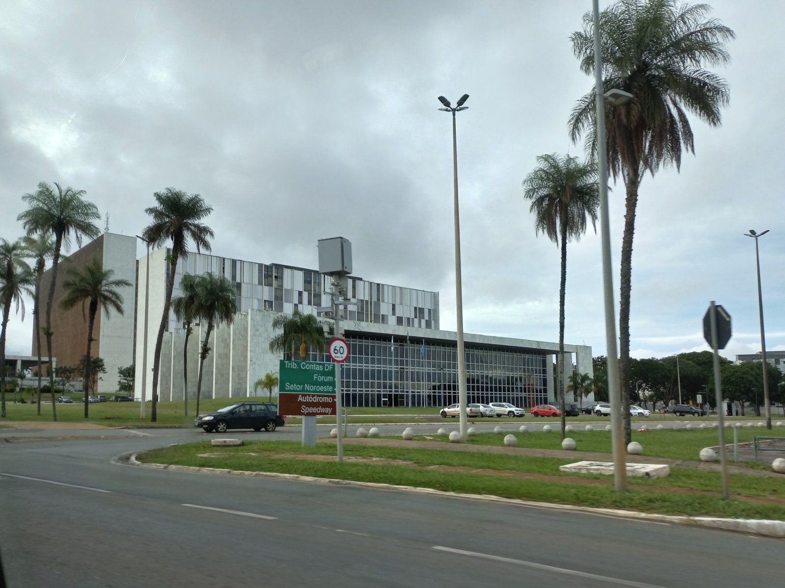 Fachada do Tribunal de Contas do Distrito Federal vista da via, com palmeiras e placa indicativa Trib. Contas DF