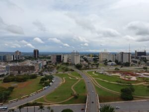 Vista aérea do Eixo Monumental, em Brasília, com carros e ônibus circulando nas pistas do Plano Piloto