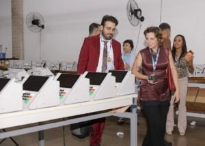 Fileira de urnas eletronicas sobre mesa em sala de preparacao da Justica Eleitoral