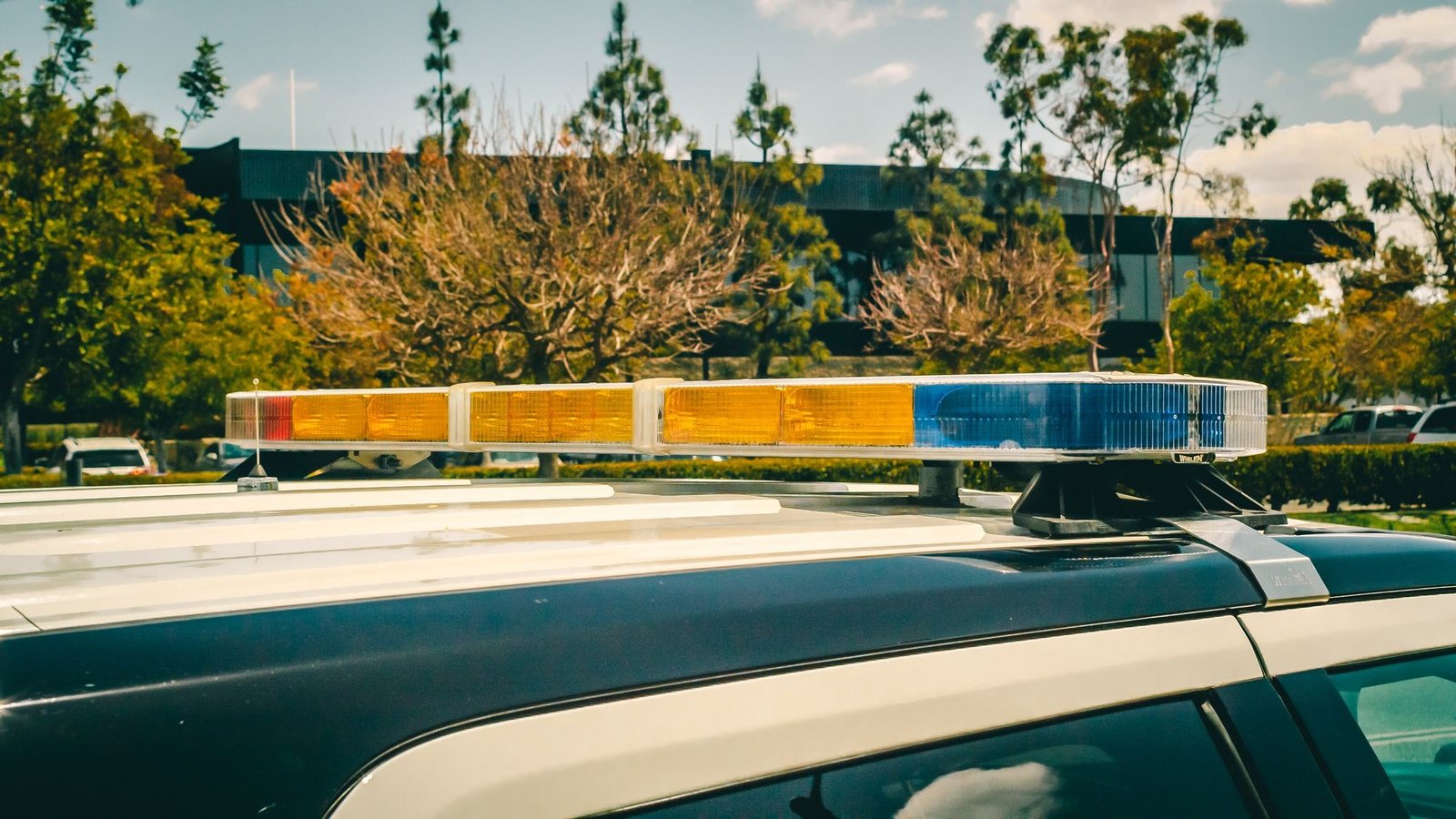 Barra de luzes de uma viatura policial em close, com árvores ao fundo