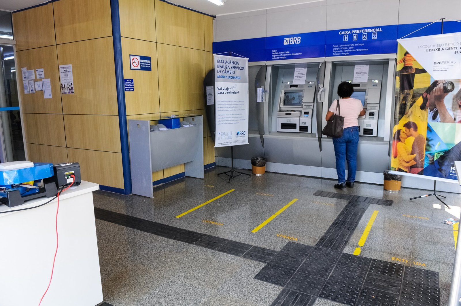 Mulher de costas usa caixa eletrônico em agência do BRB, em foto de arquivo de 2019