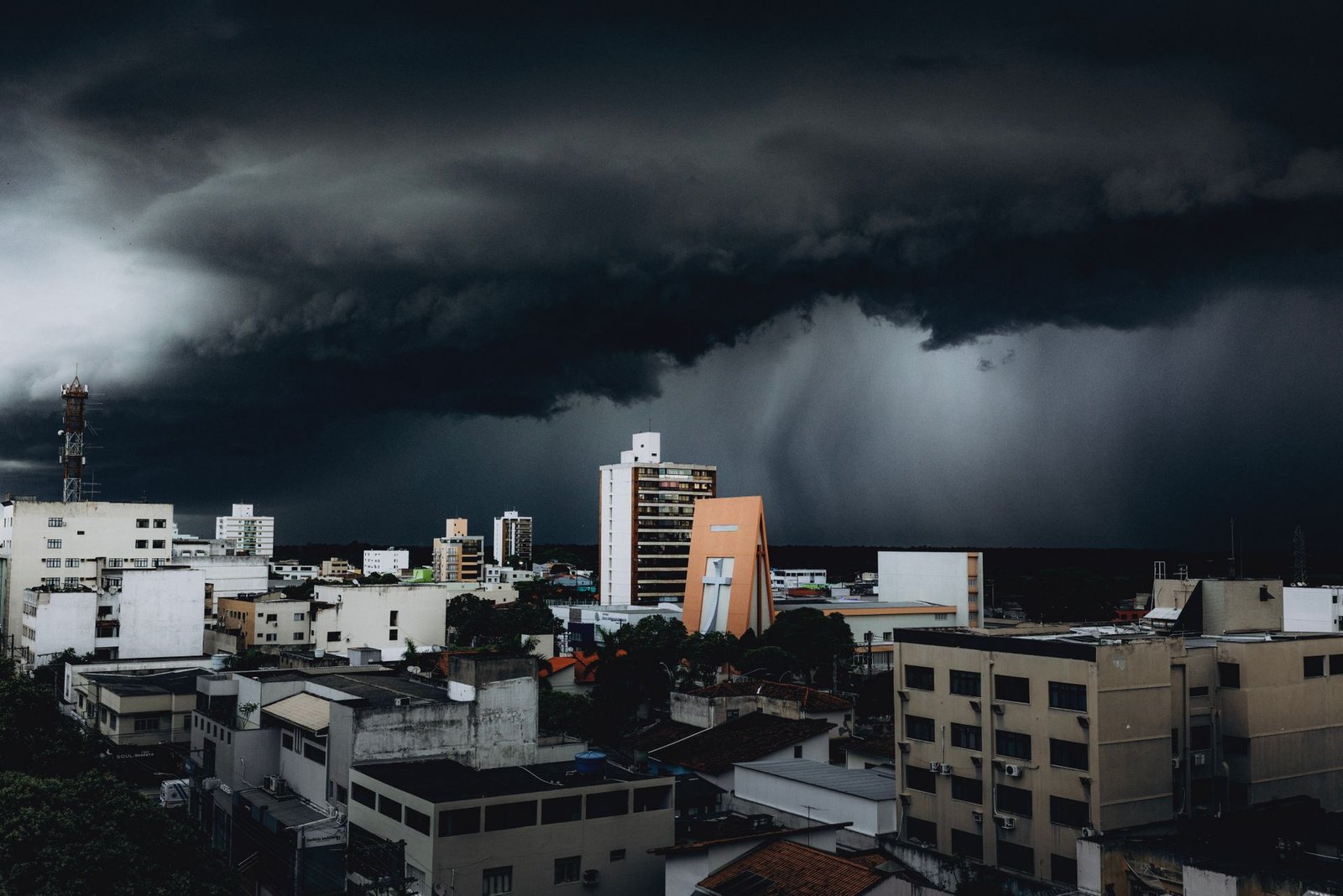 Nuvem de tempestade escura sobre os prédios de uma cidade brasileira, com chuva caindo ao fundo