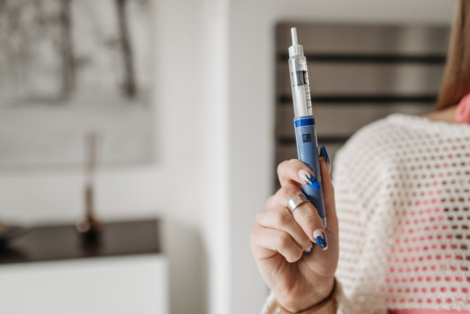 Mão feminina segura uma caneta injetável azul, em imagem ilustrativa sobre canetas aplicadoras de medicamento