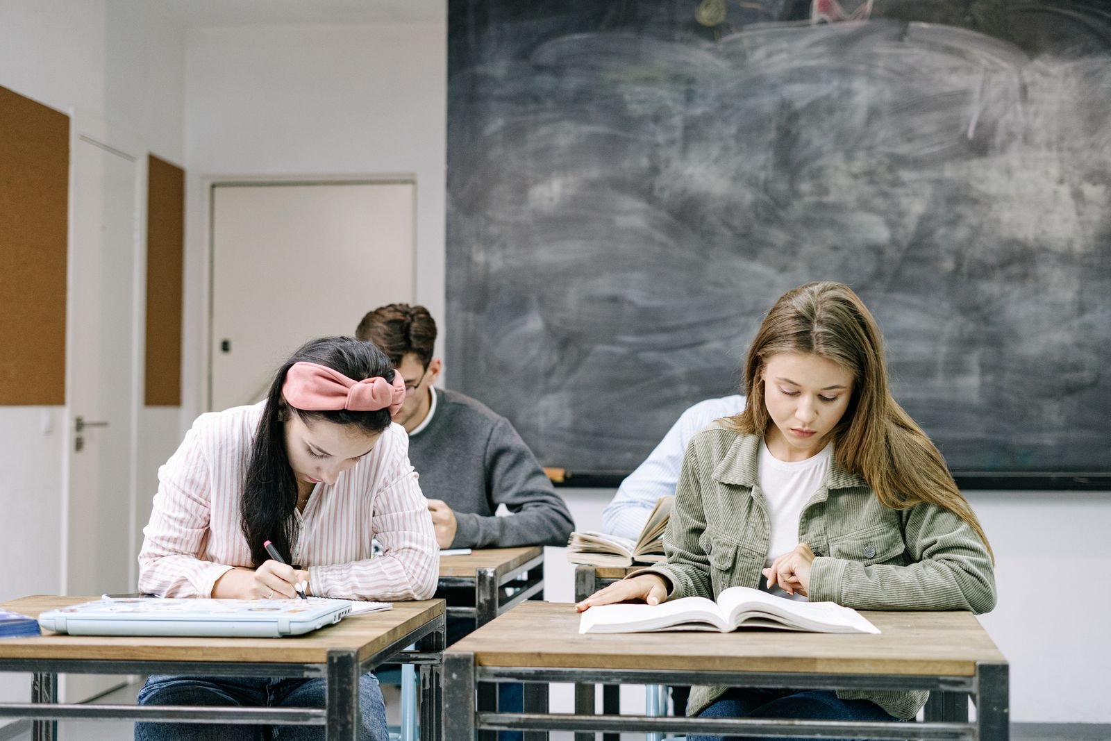 Estudantes estudam em sala de aula, com livros e cadernos abertos