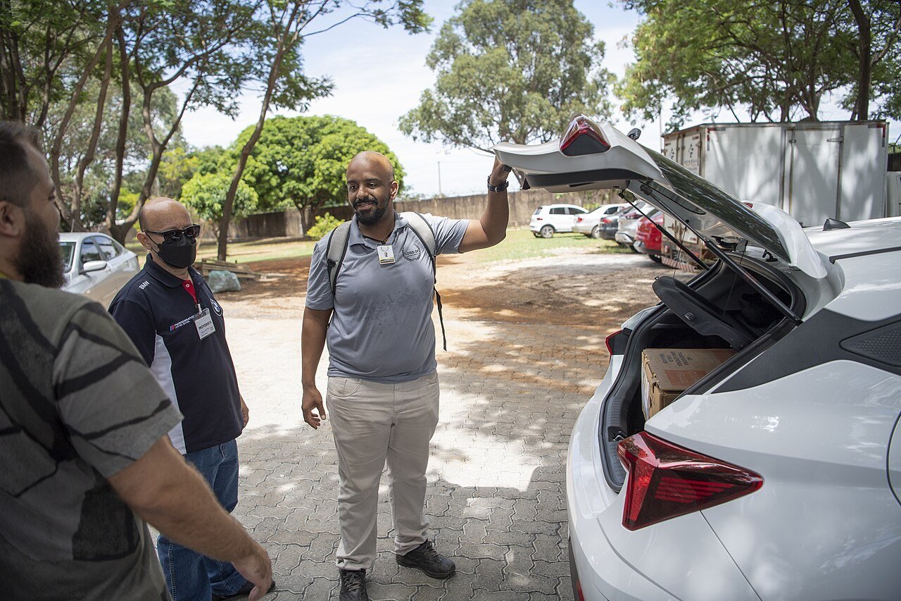 Mesários conversam ao lado de um carro, com caixas de urnas eletrônicas no porta-malas, durante o segundo turno de 2022 (foto de arquivo)