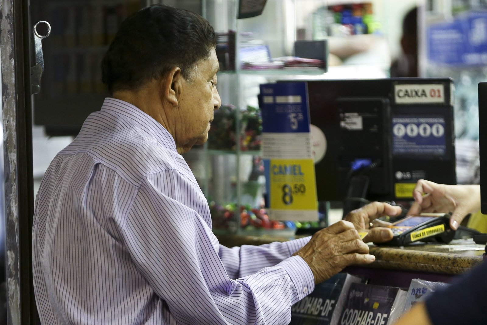 Idoso usa a maquininha de pagamento em um balcão de banca em Brasília, em foto de arquivo