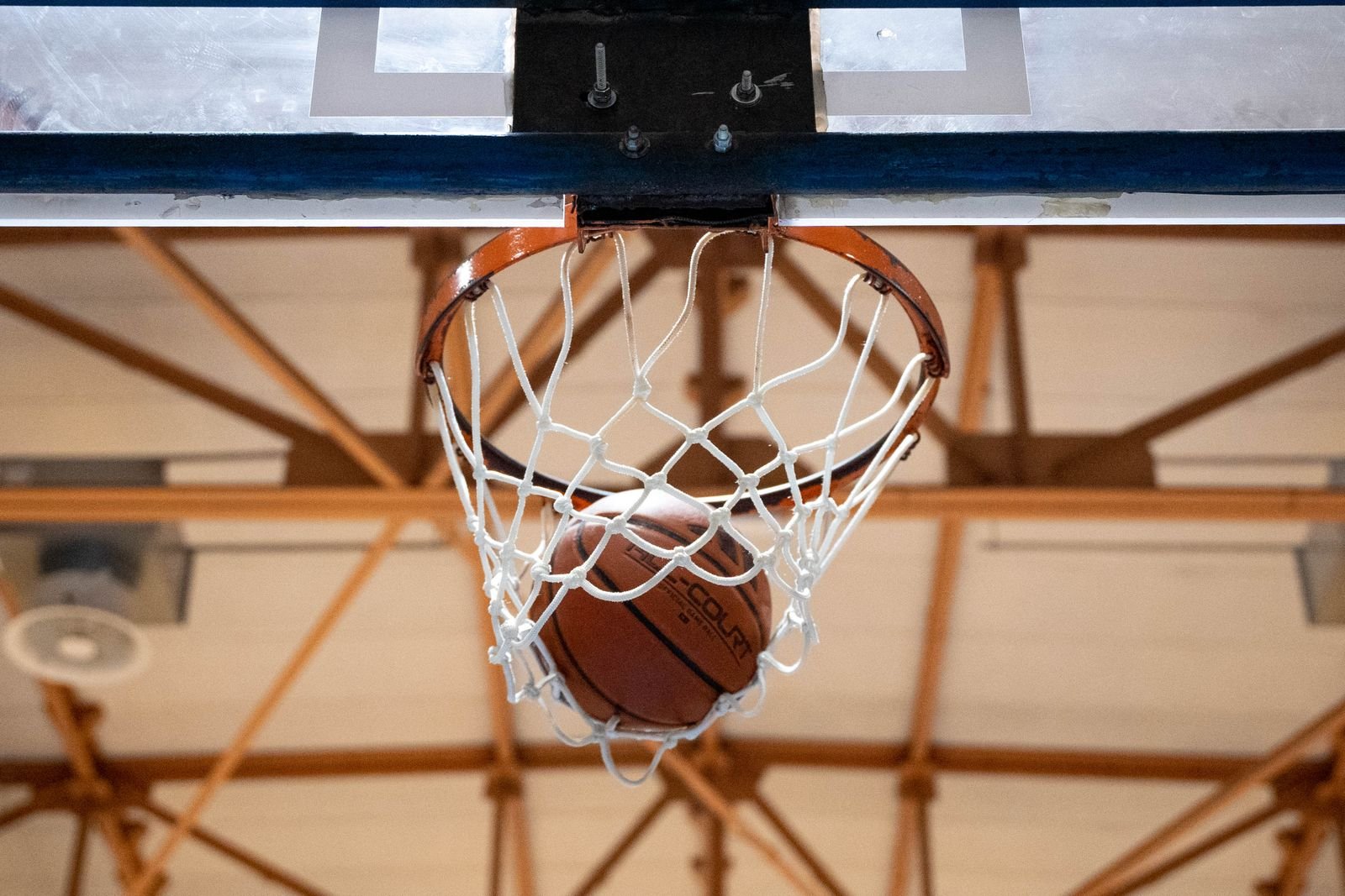 Bola de basquete passando pela cesta em ginásio, foto de arquivo de banco de imagens