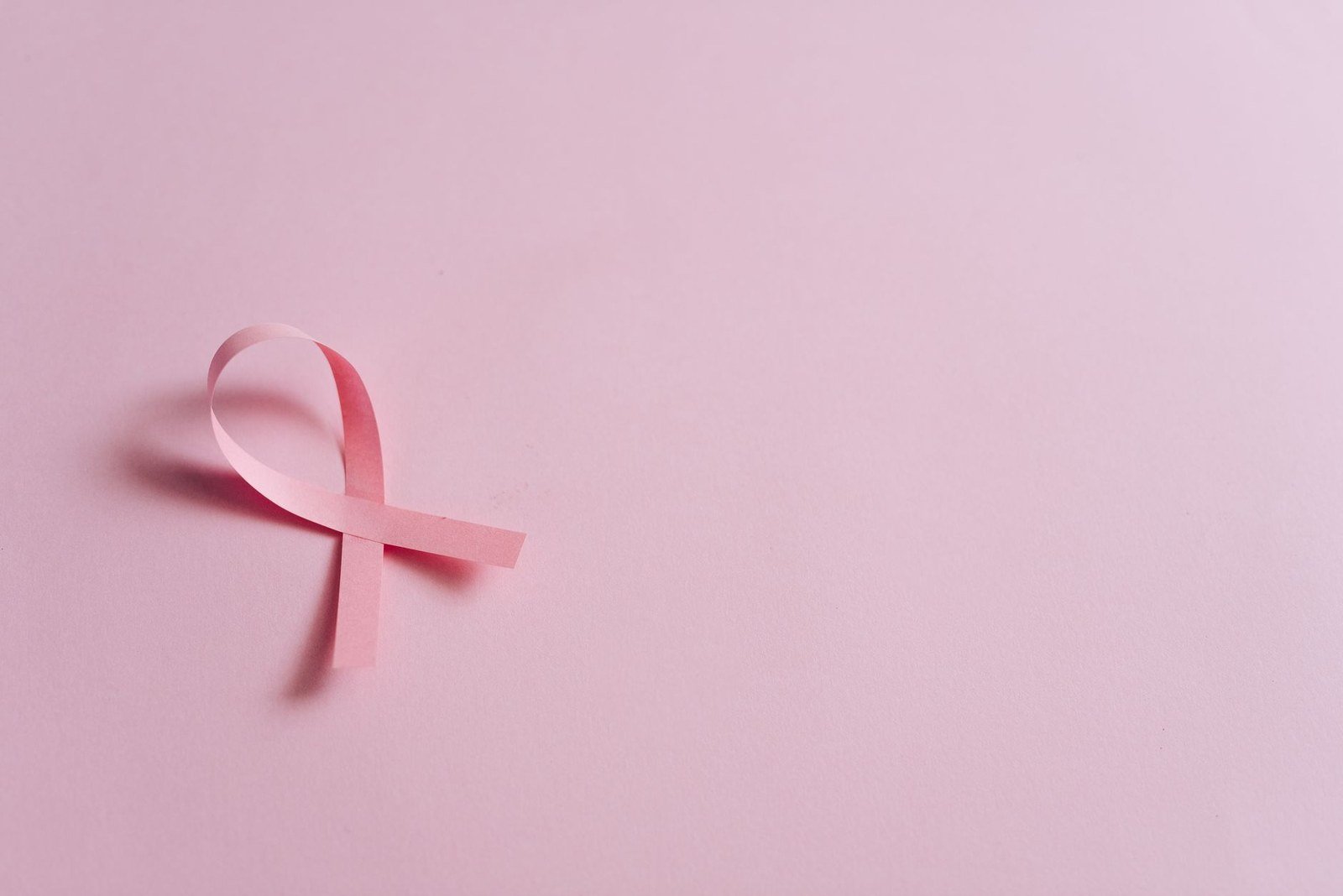Laço rosa, símbolo do Outubro Rosa, sobre fundo rosa claro