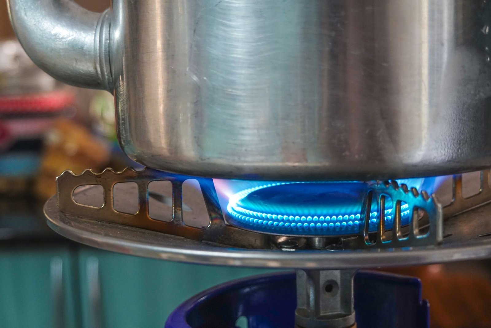 Panela de alumínio sobre a chama azul de um fogão a gás, em close