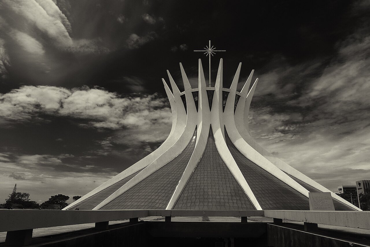 Catedral Metropolitana de Brasília sob céu carregado de nuvens, em foto em tons de sépia