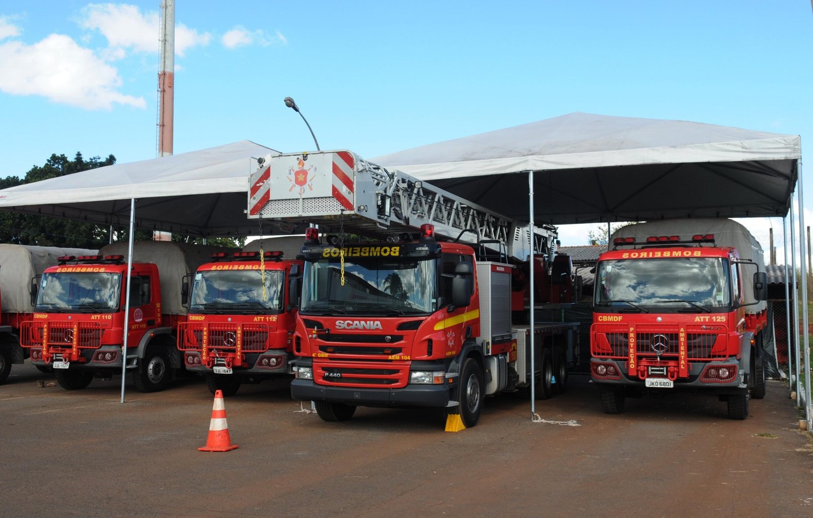 Viaturas do Corpo de Bombeiros Militar do DF, entre elas uma autoescada, estacionadas sob tendas em quartel