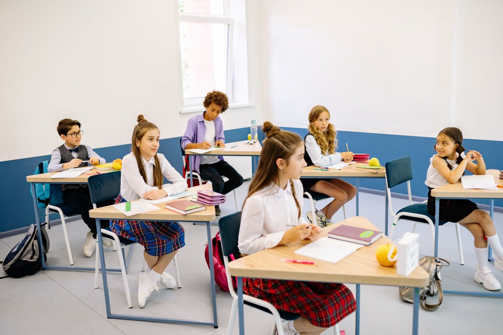 Estudantes uniformizados sentados em carteiras em sala de aula, foto de arquivo