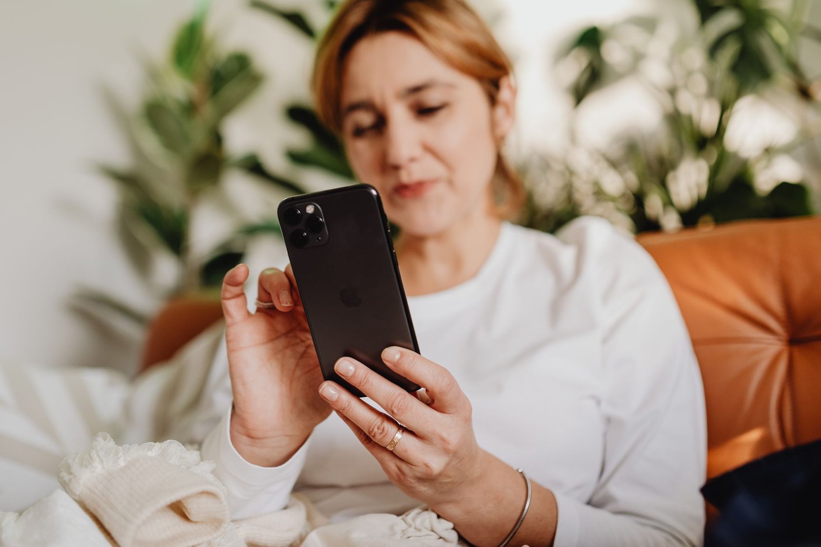 Mulher olha a tela de um celular sentada em casa