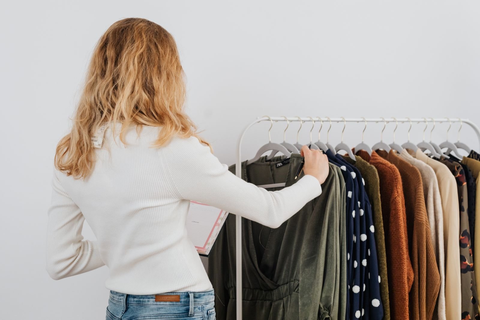 Mulher de costas escolhe peças em arara de loja de roupas