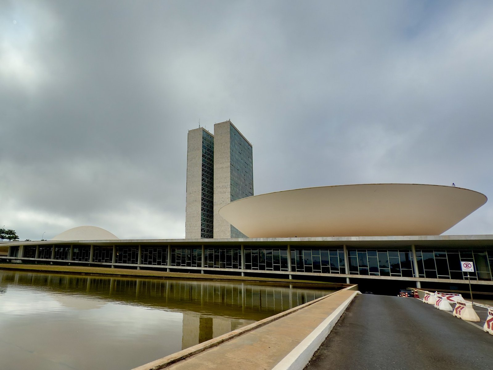 Fachada do Congresso Nacional em Brasília, com as duas torres e a cúpula da Câmara sob céu nublado