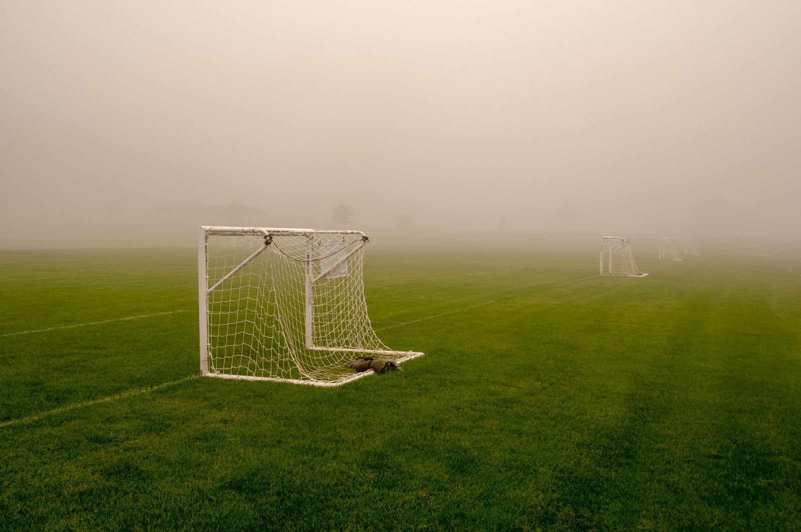 Gol de futebol com rede em um campo de grama coberto por névoa (imagem ilustrativa)