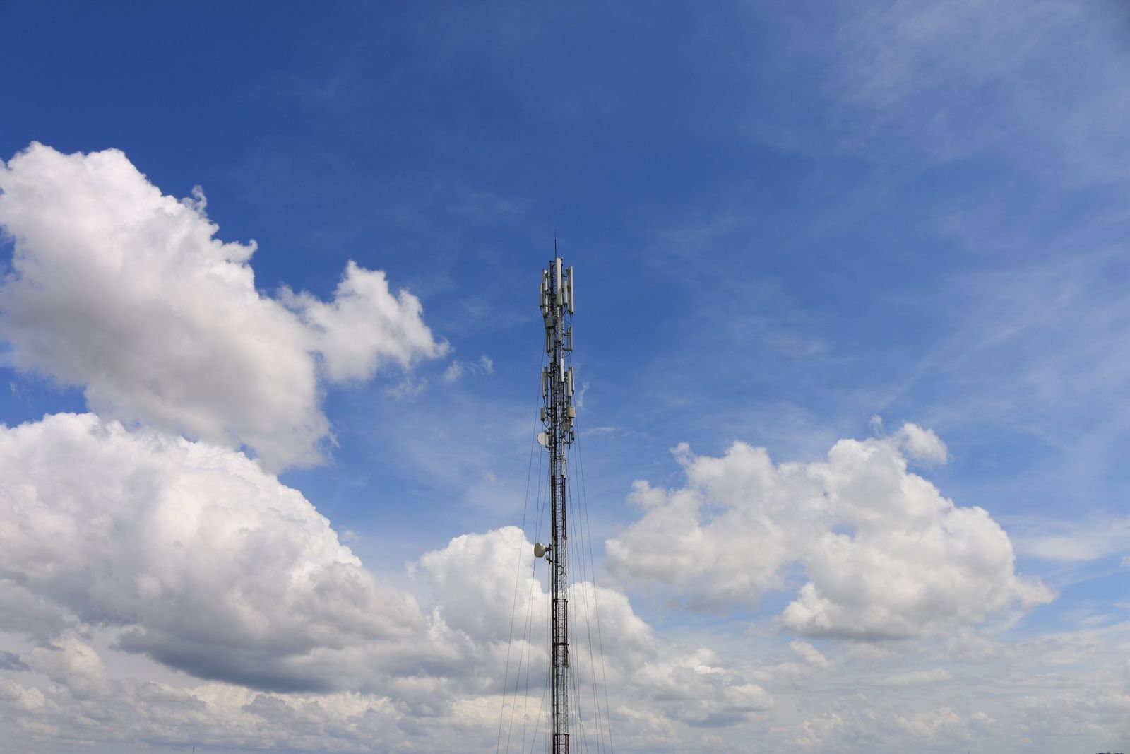 Torre de telecomunicações com antenas contra céu azul e nuvens, imagem ilustrativa