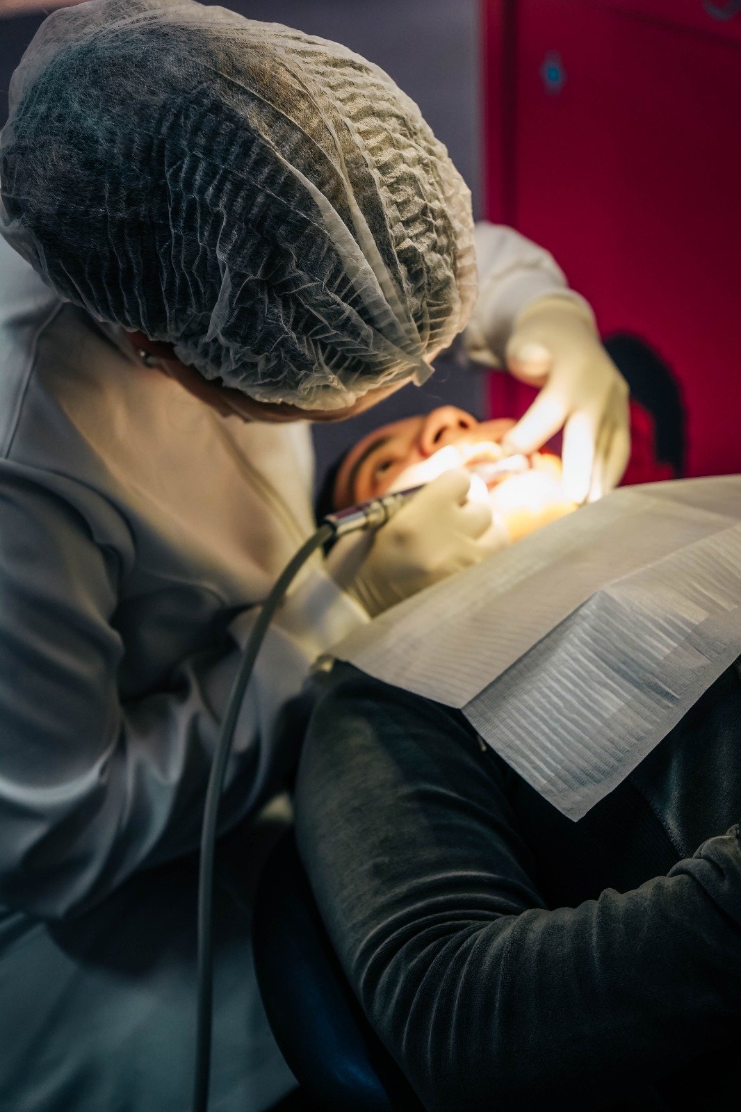 Dentista de touca e máscara durante atendimento no Odonto em Ação