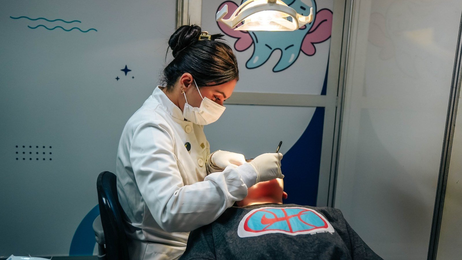 Dentista de jaleco branco ao lado do mascote em forma de dente na unidade do Odonto em Ação